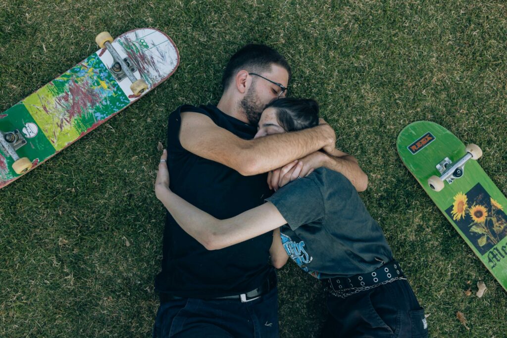 young couple holding one another next to skateboards