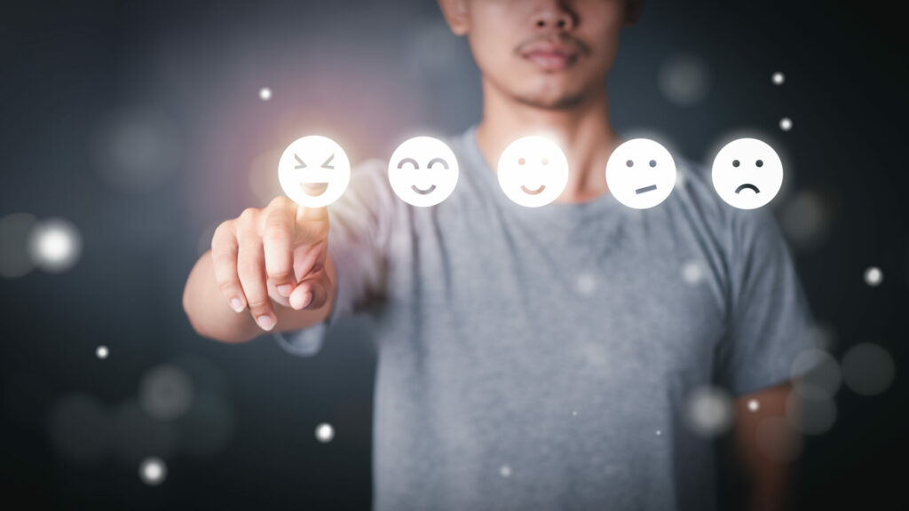 man poiting at screen with different smiley faces