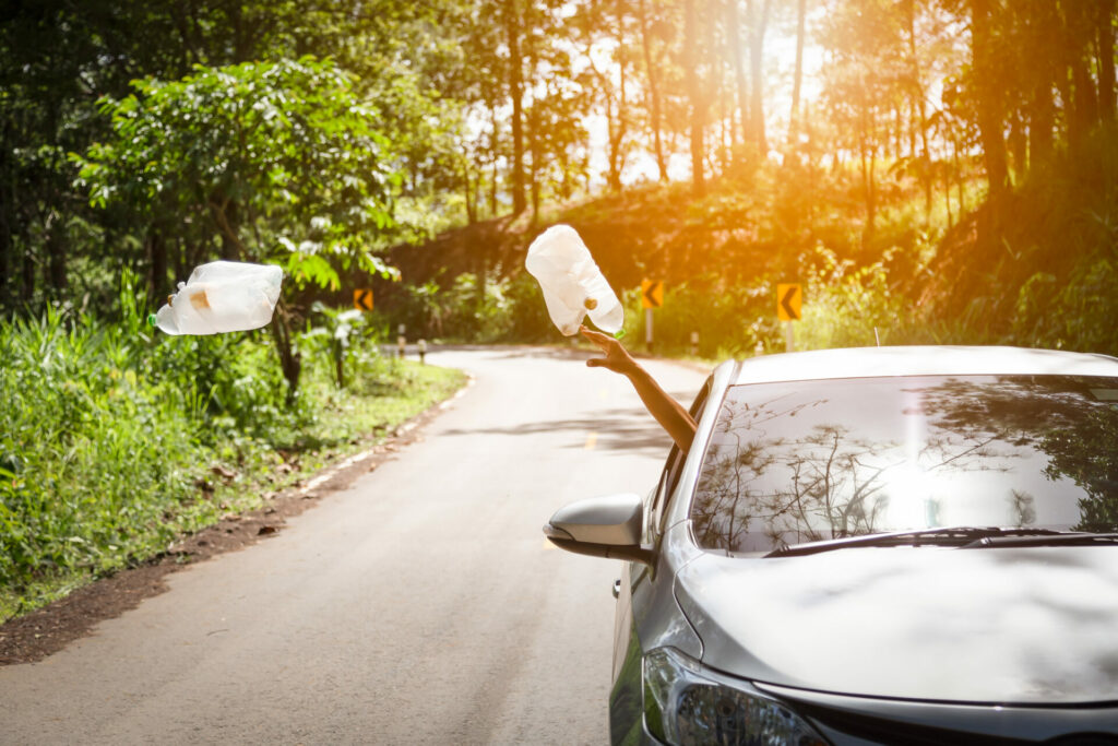 man throwing plastic litter out of car not caring about climate change