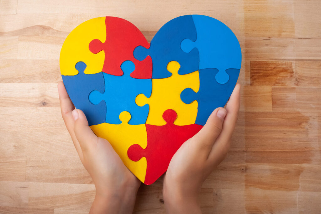 Colorful puzzle heart in hands