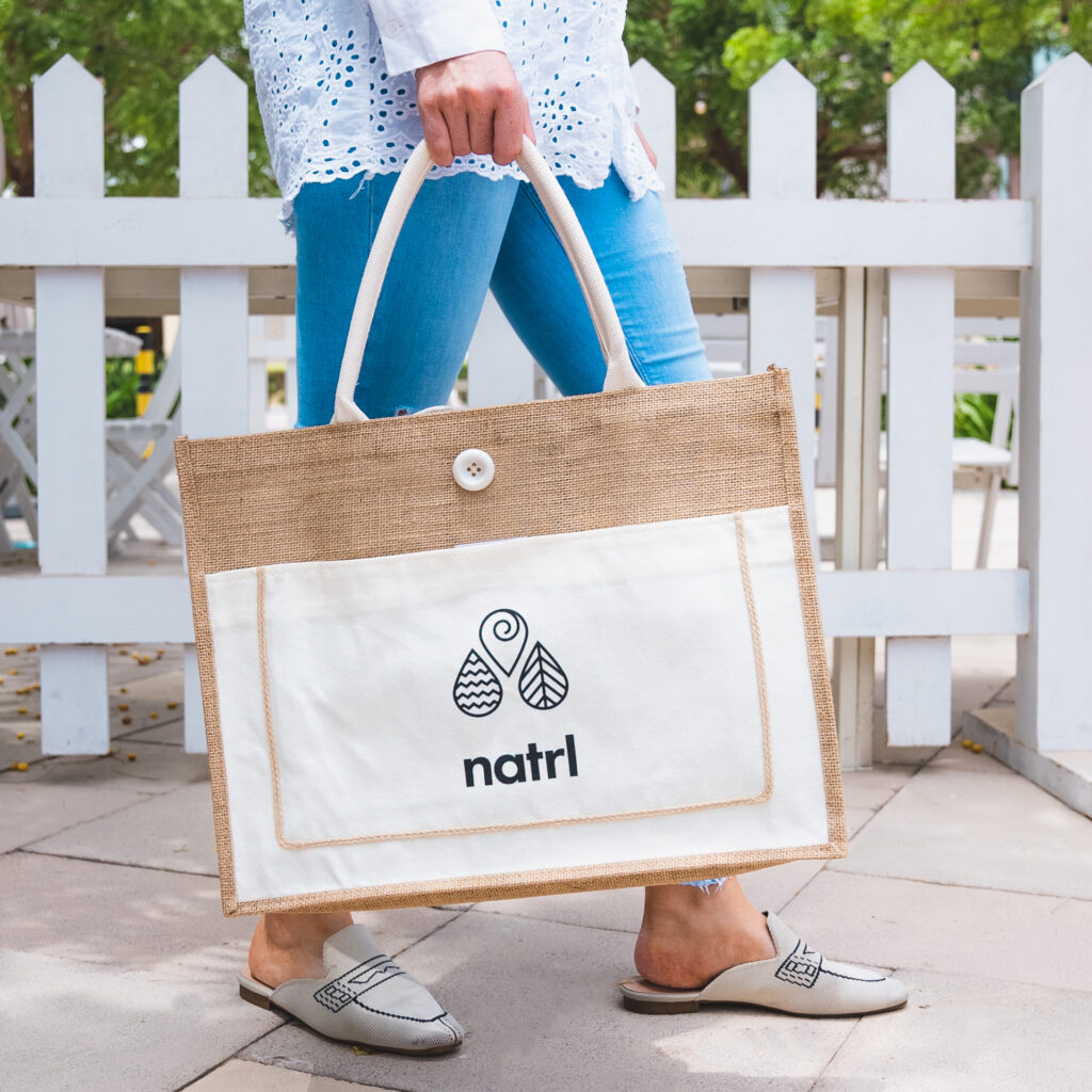 natrl water reusable bag being held by lady walking 