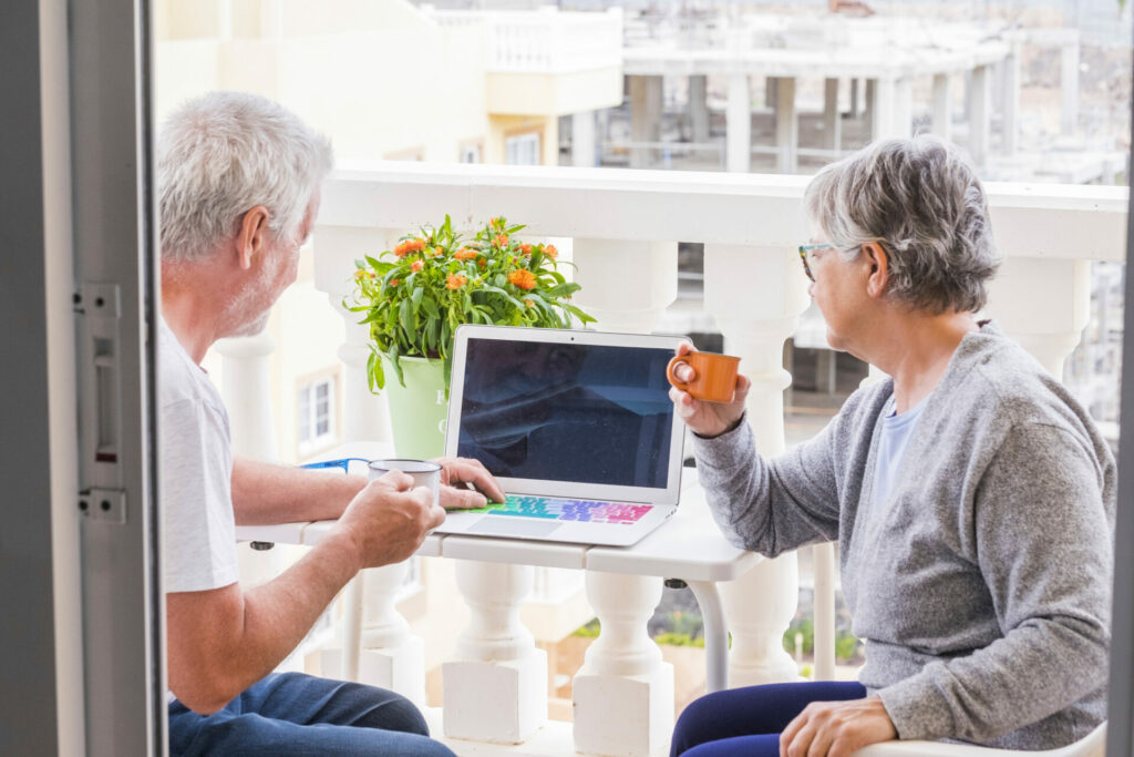 couple of senior citizens on a terrace with a laptop and coffee 