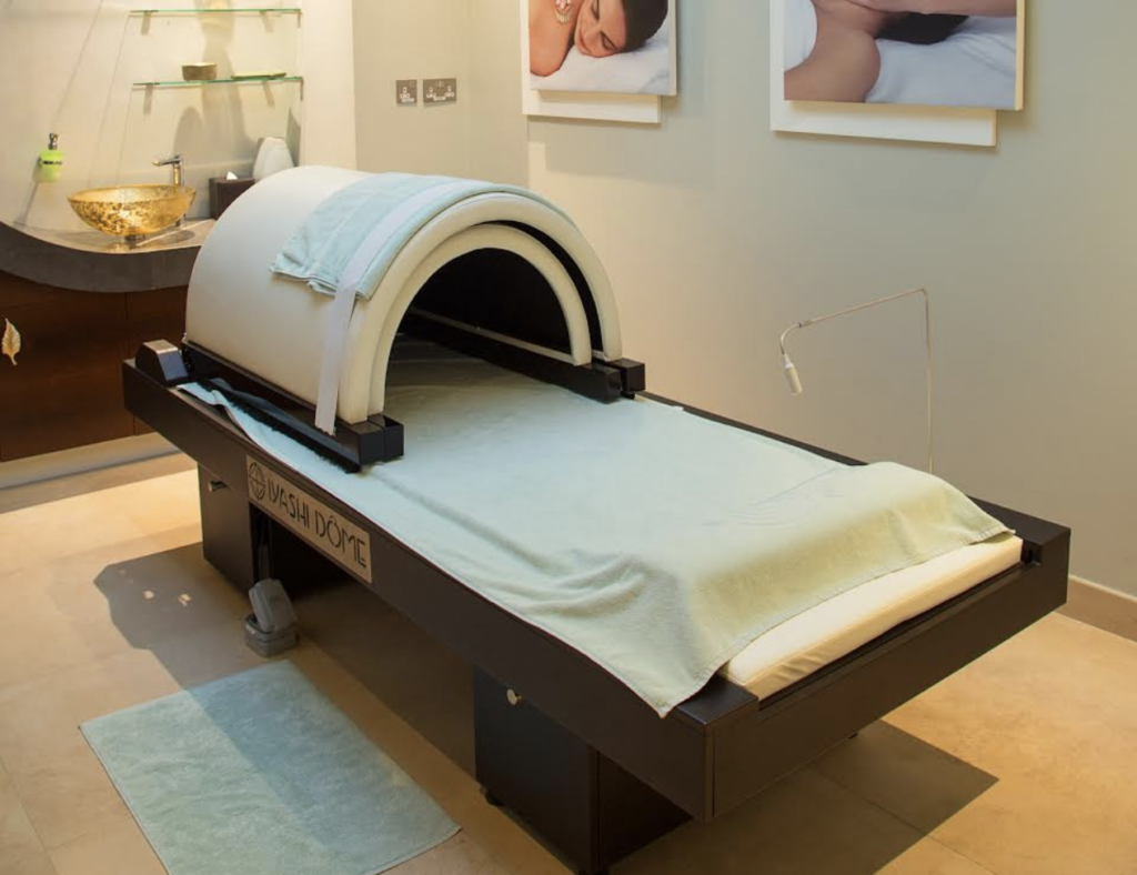 Shows the Iyashi Dôme detox machine which looks like an MRI tunnel, in a spa setting 