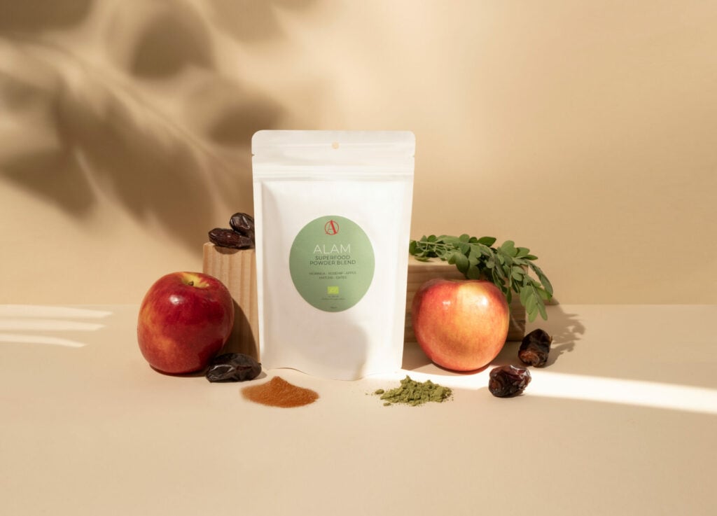 Alam natural beauty pouch stood next to apples and greenery 