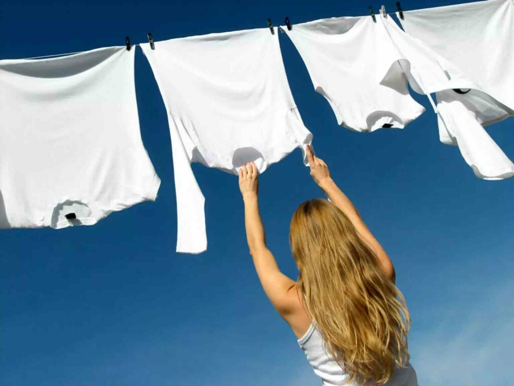 woman hanging whites on a laundry line as a way to make clothes last longer