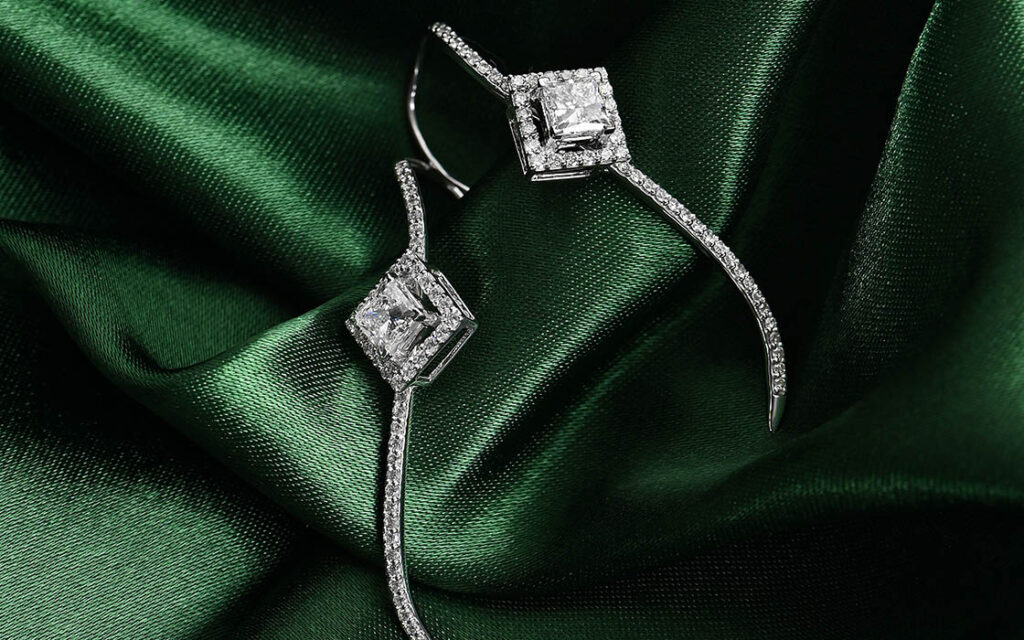 lab-grown diamond earrings on green material 