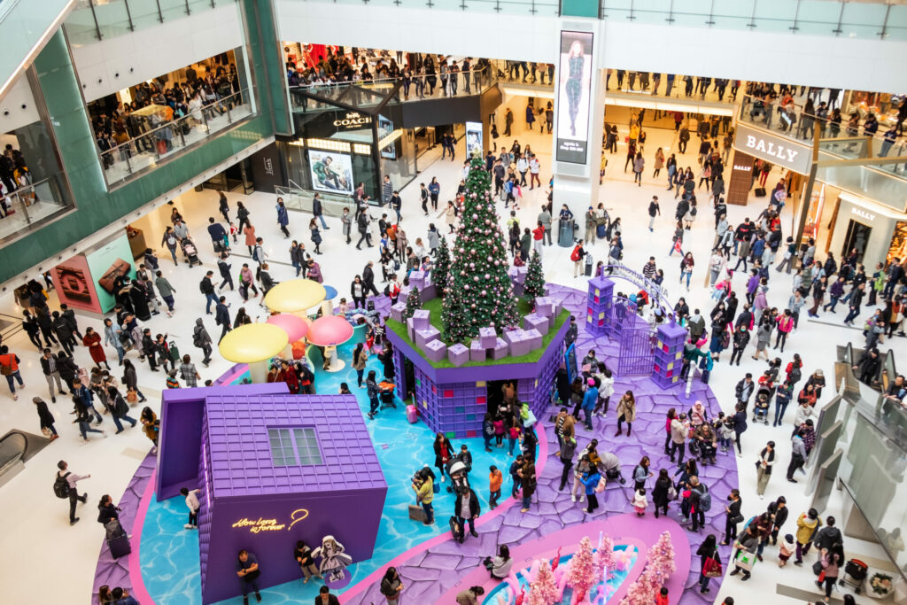 Christmas shoppers in a mall with a big Christmas tree centre as the opposite of Buy Nothing Day 