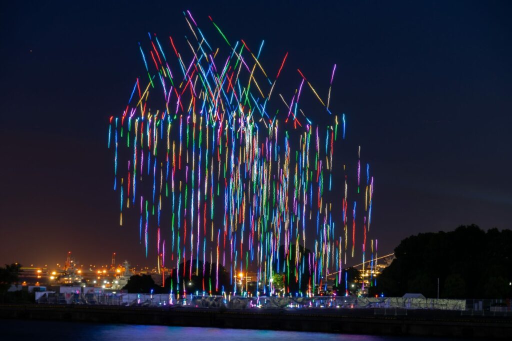 Multicoloured drone show lighting up the sky with a city in the distance 