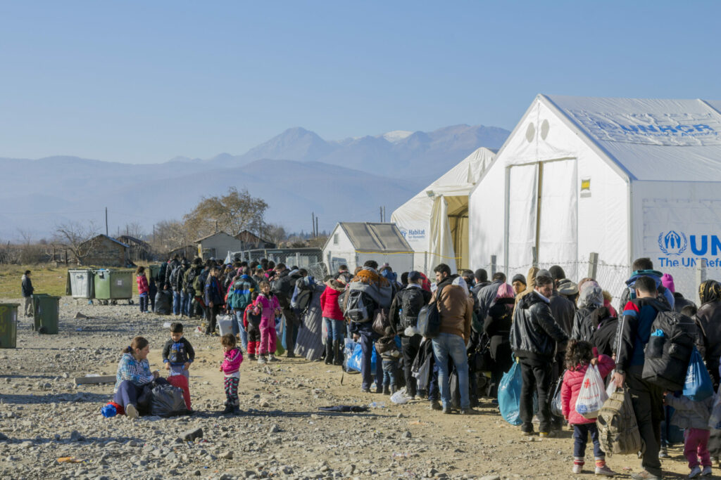 mass migration with refugees stood in line at a UNHCR camp