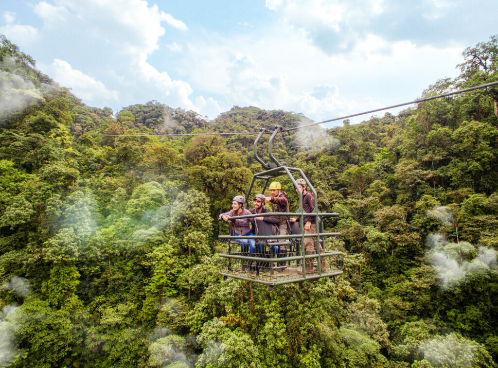 Tourists helping with conservation in a pulley lift surrounded by rainforest