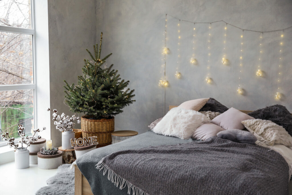 Grey and white bedroom with potted Christmas tree in the corner 