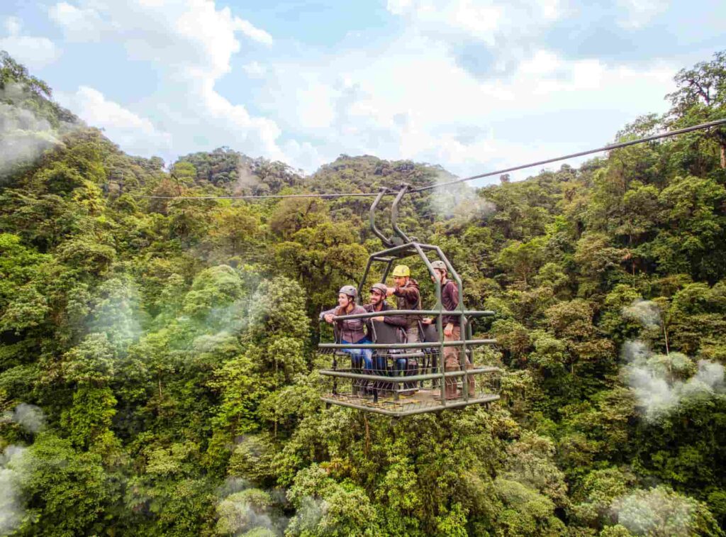 Tourists helping with conservation in a pulley lift surrounded by rainforest 