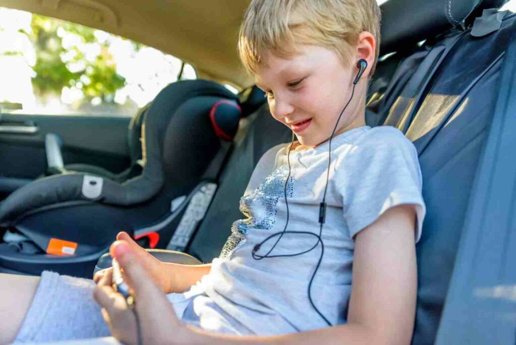 boy looking at mobile phone in back of car