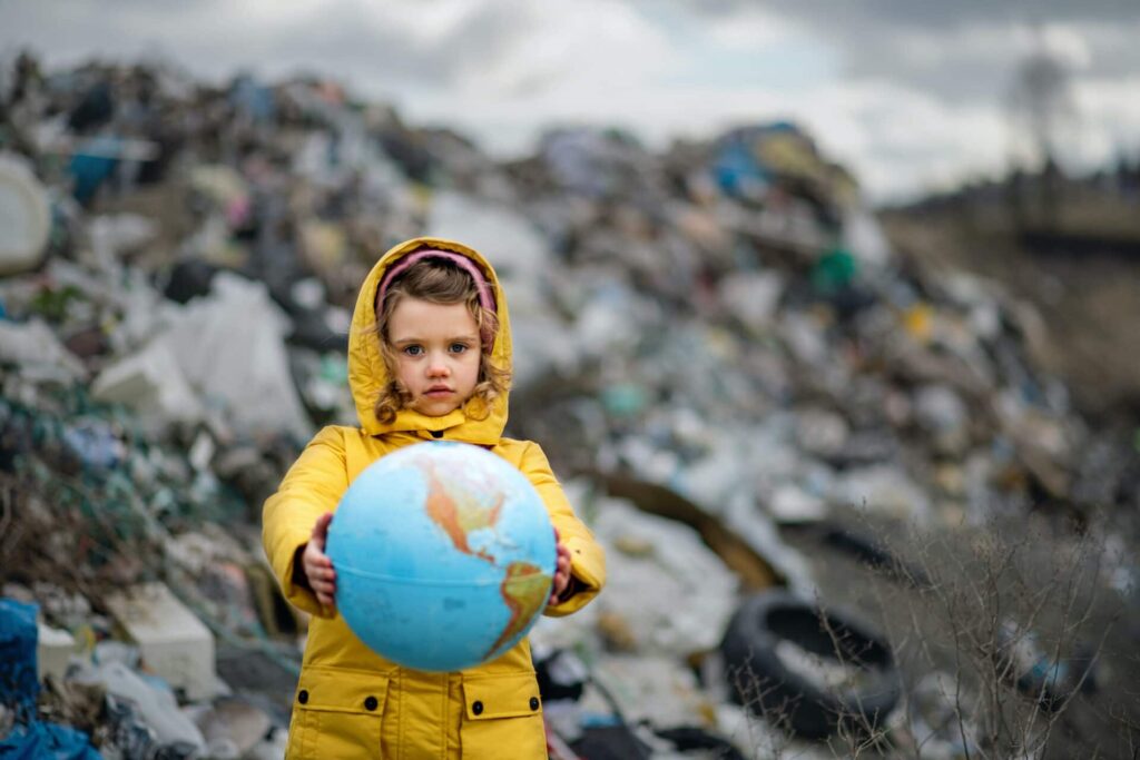 girl holding globe on landfill against climate crisis