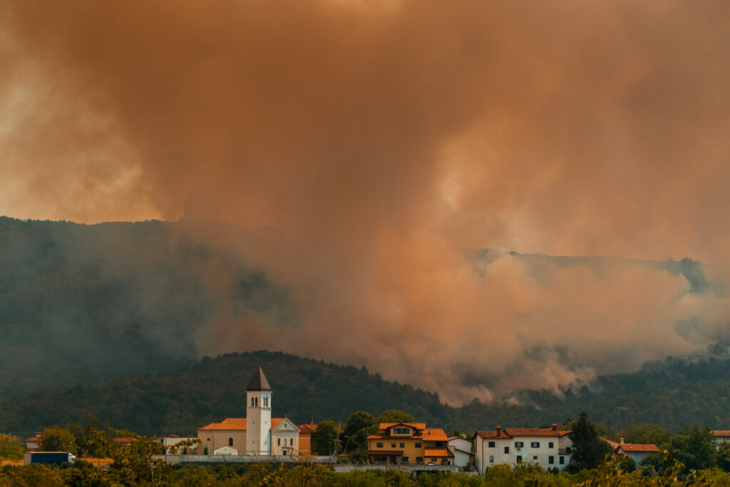 wildfire ravages  forest around a town in Europe 