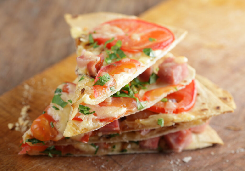 tomato and cheese tortilla pizzas stacked 