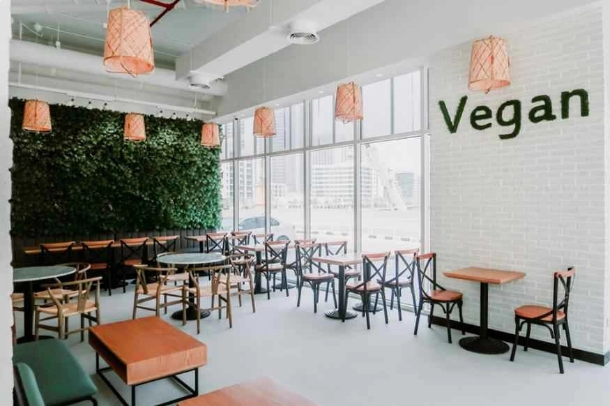 white tiled restaurant with leafy wall and vegan written on other wall