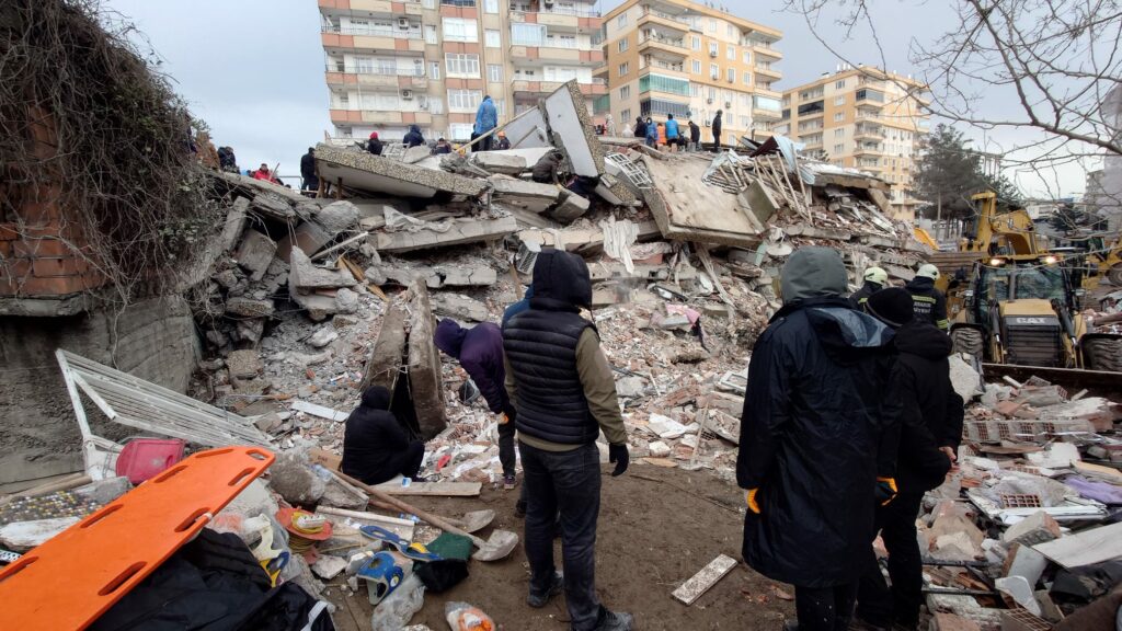 survivors watch on as rescuers look for survivors at a rubble site left from the devastating earthquake 