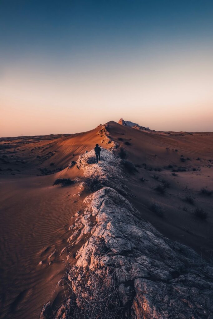 man walking in desert at sunset 