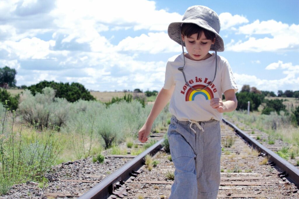 little boy in cute kid's clothing on railway tracks 
