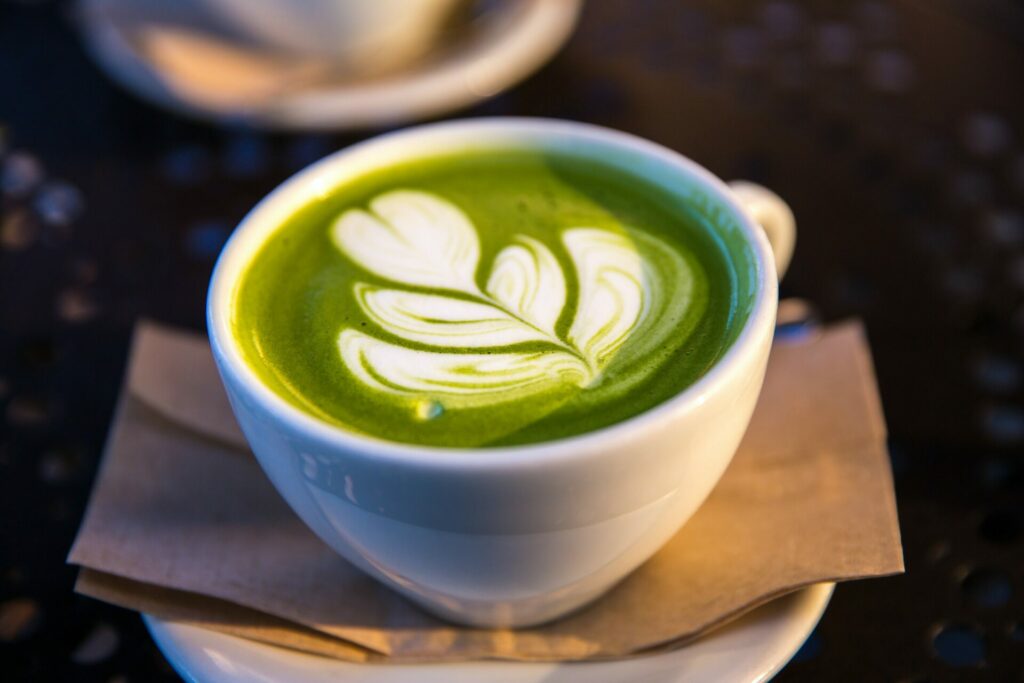 close up of matcha latte with leaf design in frothy milk