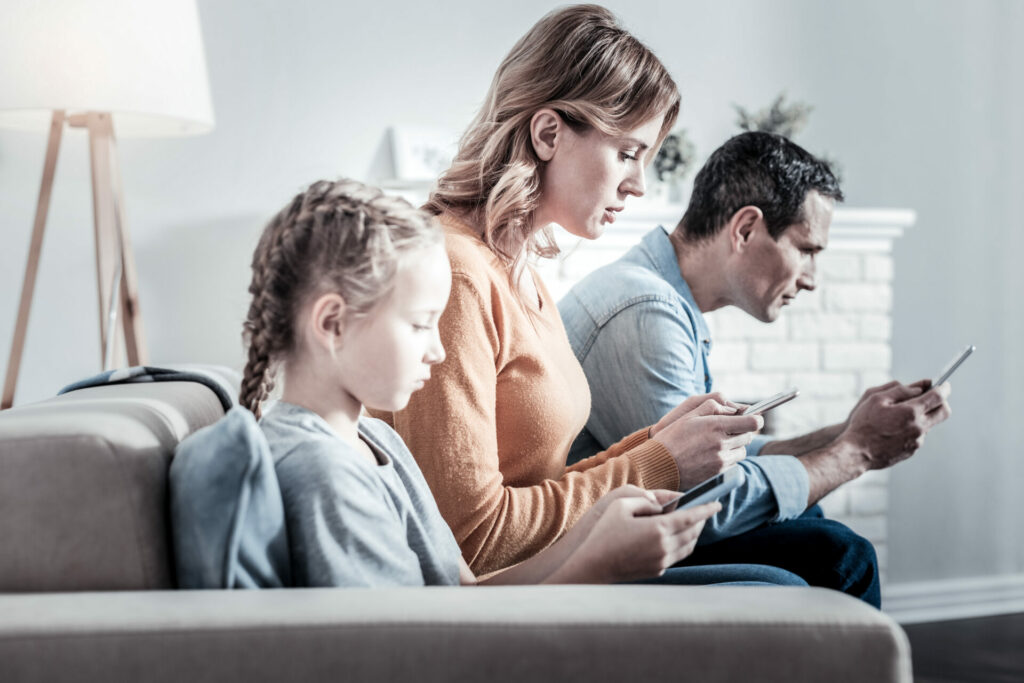 entire family of parents and child all online while sat on sofa 