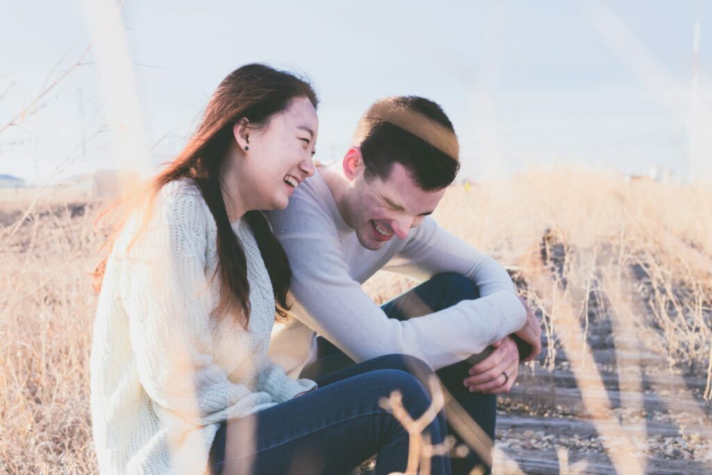 couple laughing on old rail track in field 