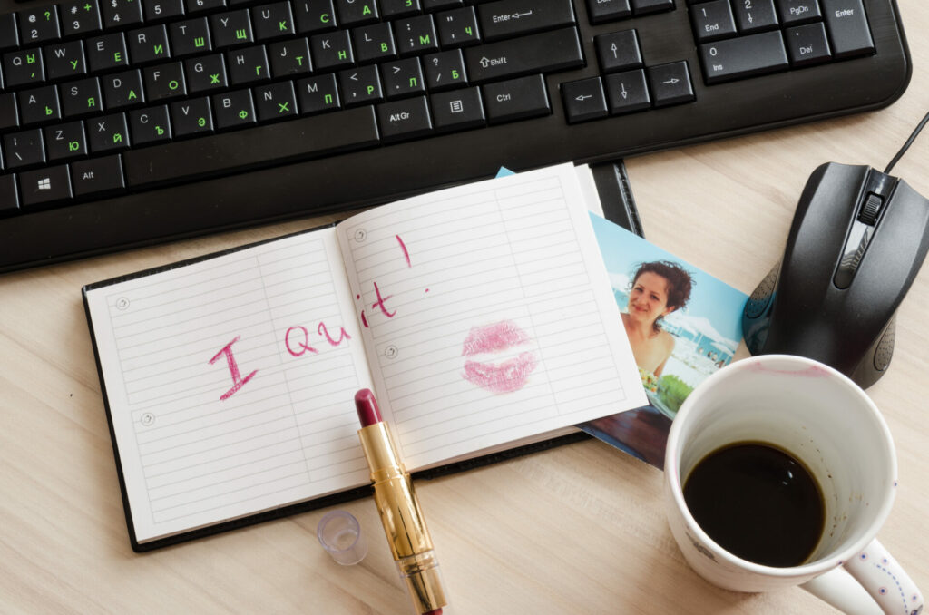 i quit written in lipstick in notebook on office desk 