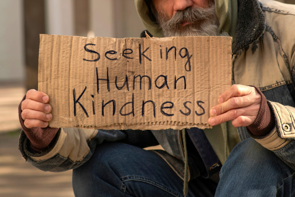 man holding sign saying seeking human kindness