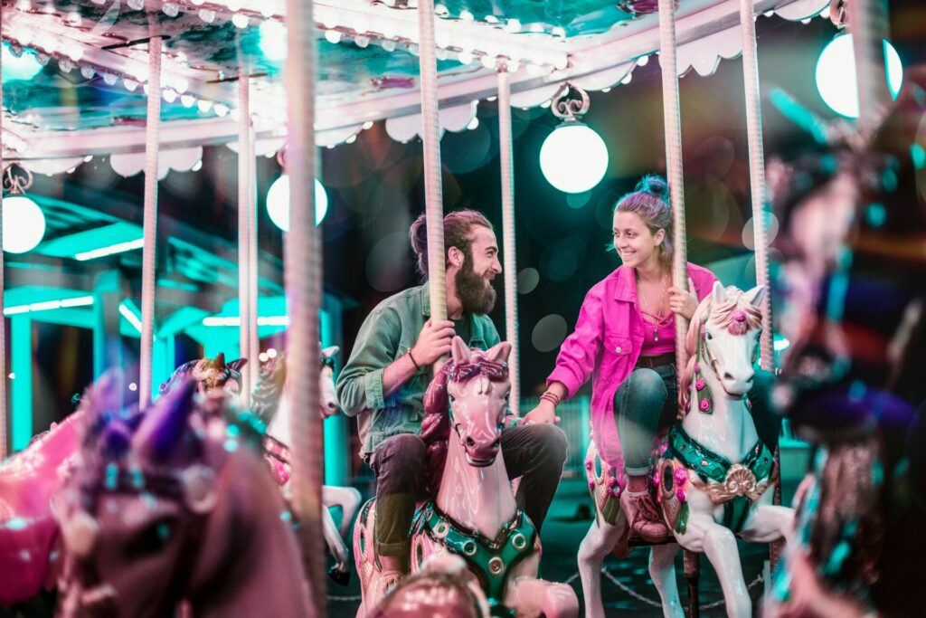 couple on carousel smiling at each other looking in love 