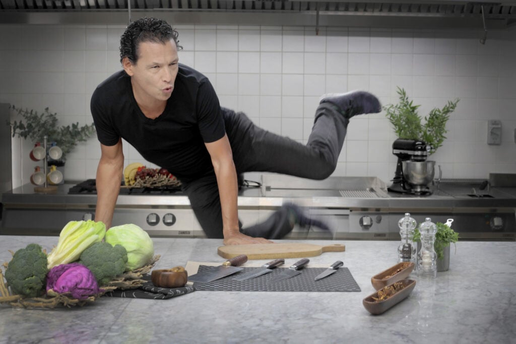 Bobby Chinn jumping in the air near kitchen counter 