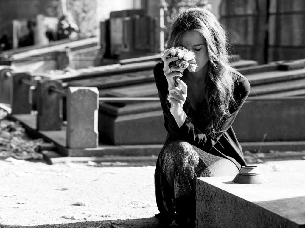 a woman at a graveside holding a bunch of flowers on Mother's Day