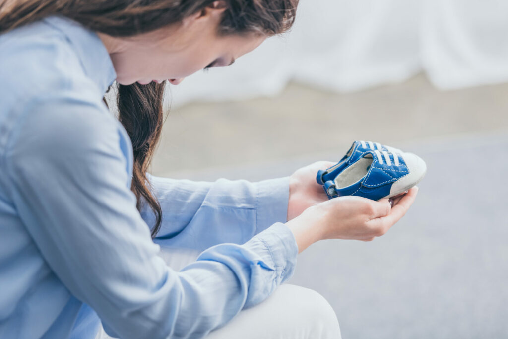 a woman holding a pair of baby shoes depicting grief and loss