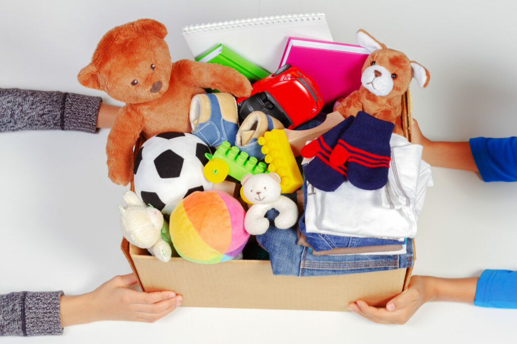 Kids hands with a donatation box with clothes, books and toys, 