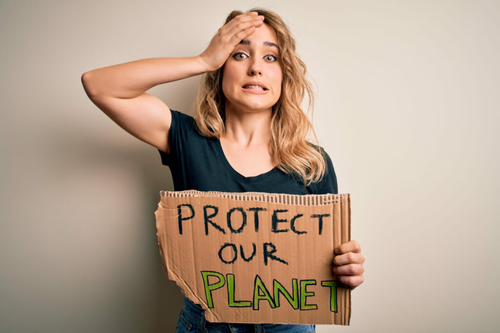 woman with climate crisis depression holding up sign saying protect our planet while looking worried 