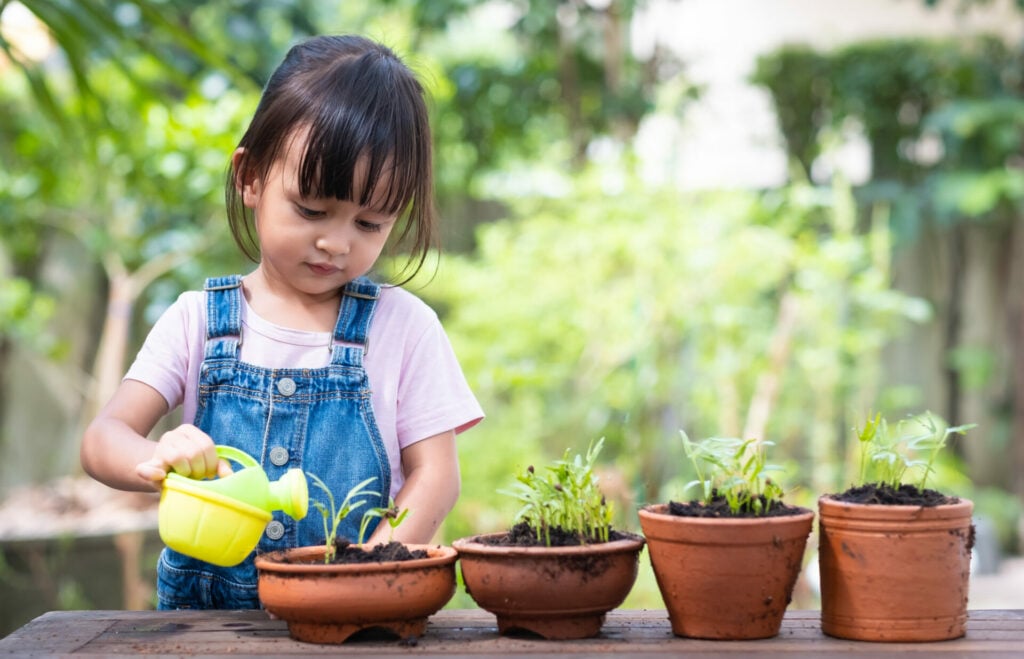 little girl watering pot plants as an eco-parenting activity 