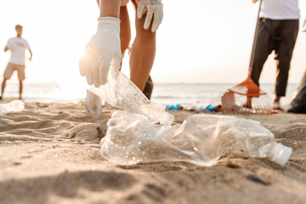 hand collecting plastic bottles from beach 