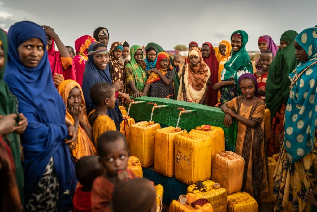 women stand around water bottles at an aid camp in Somalia 