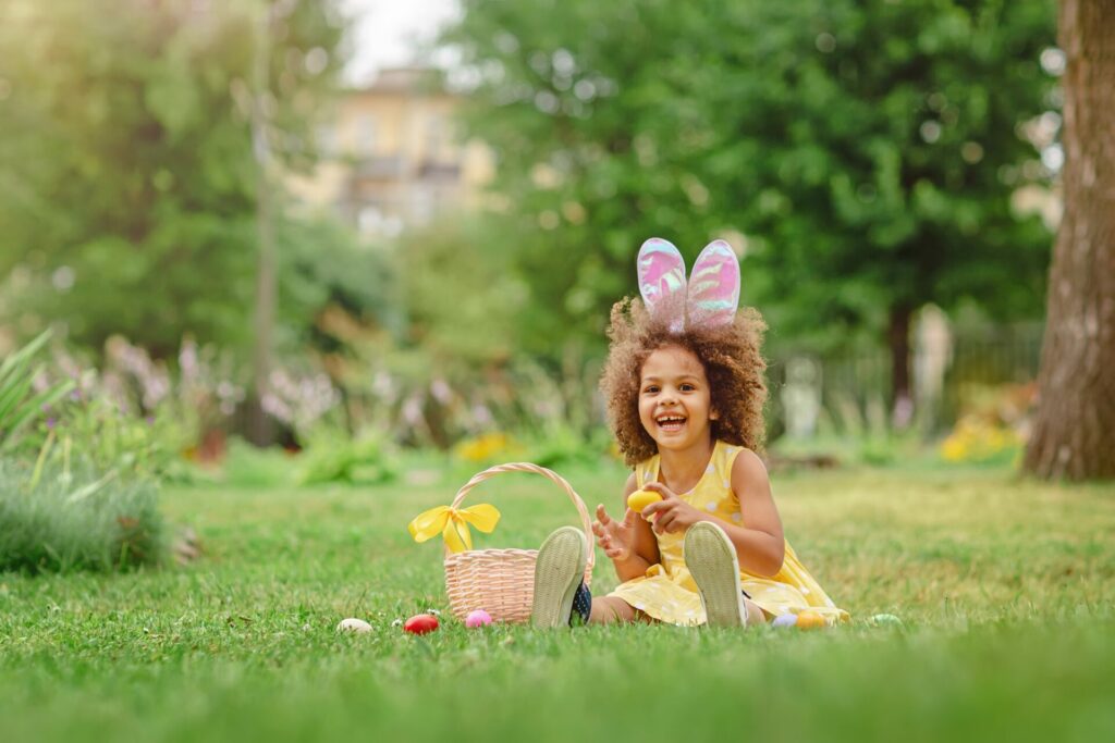 girl in easter bunny ears doing egg hunt in garden 