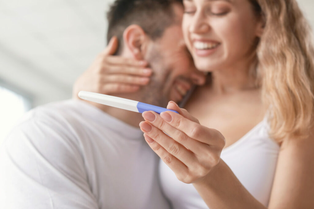 following a plant-based fertility diet can help couples have a baby - happy couple looking at positive pregnancy test 