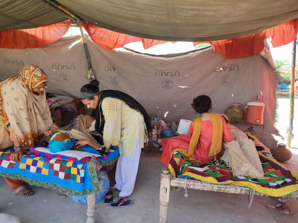 Neha Mankani listening to a woman in a makeshift tent in her rols as founder of mama baby fund 