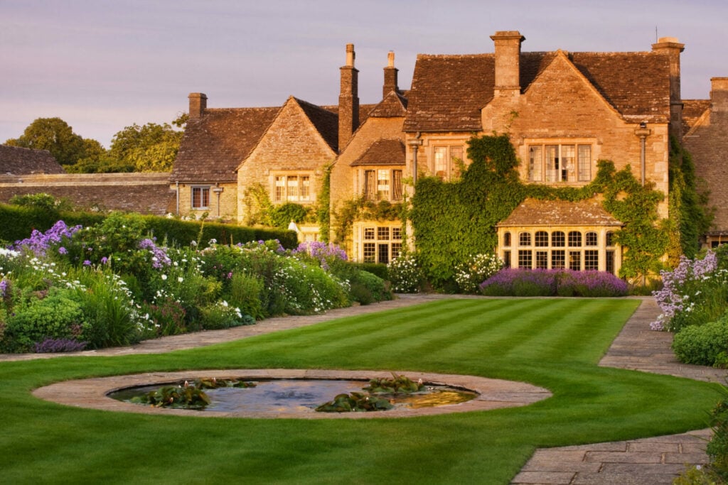 manor house with green lawn and purple flowers