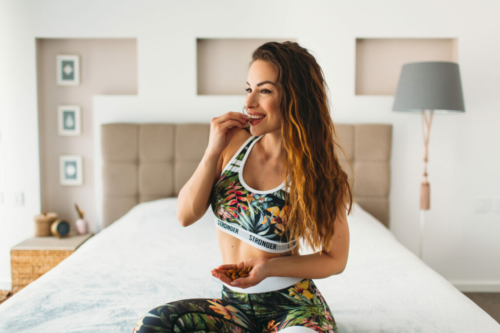 thin woman eating almonds and wearing exercise gear 