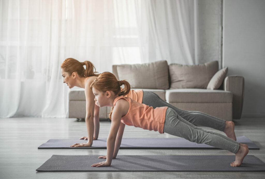 mother and young daughter doing yoga at home