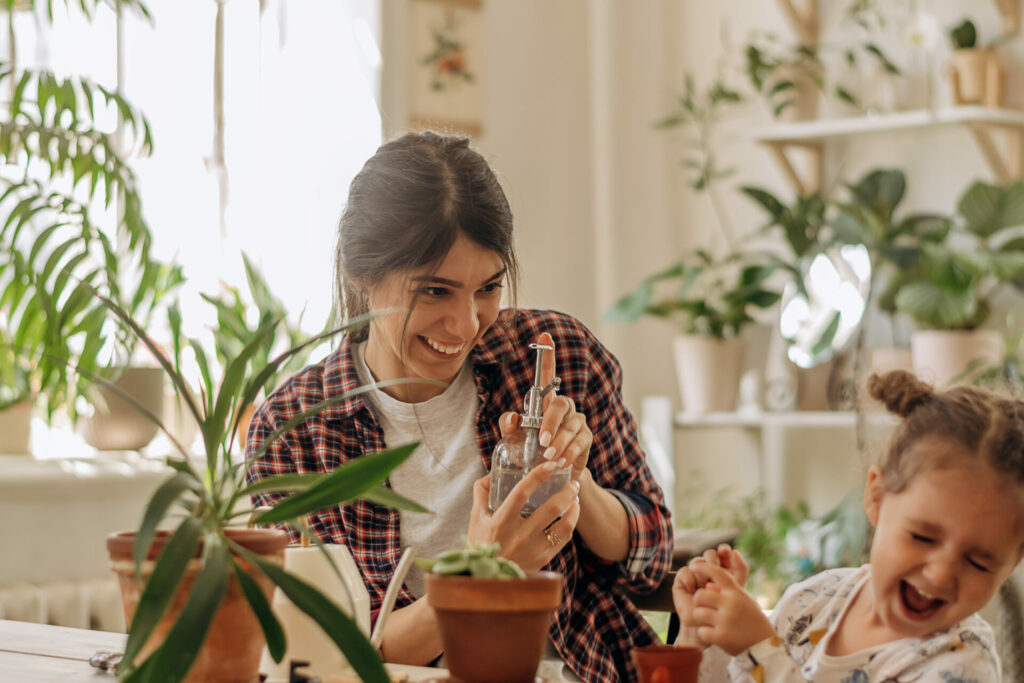 Young happy woman with a little daughter is planting houseplants. 