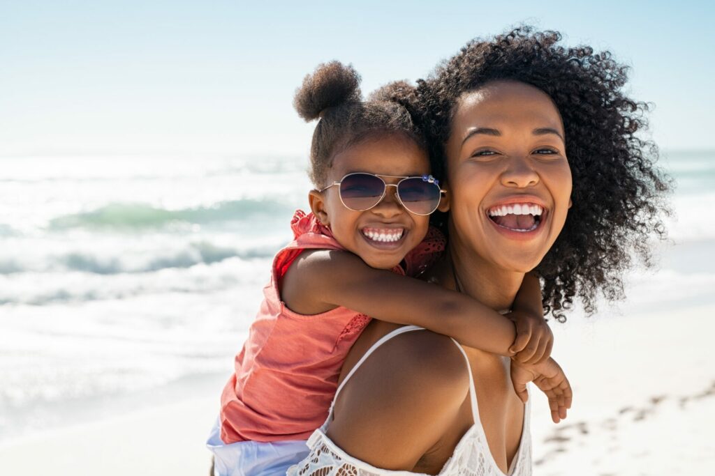 mother and baby girl on beach laughing after she manifested her life 