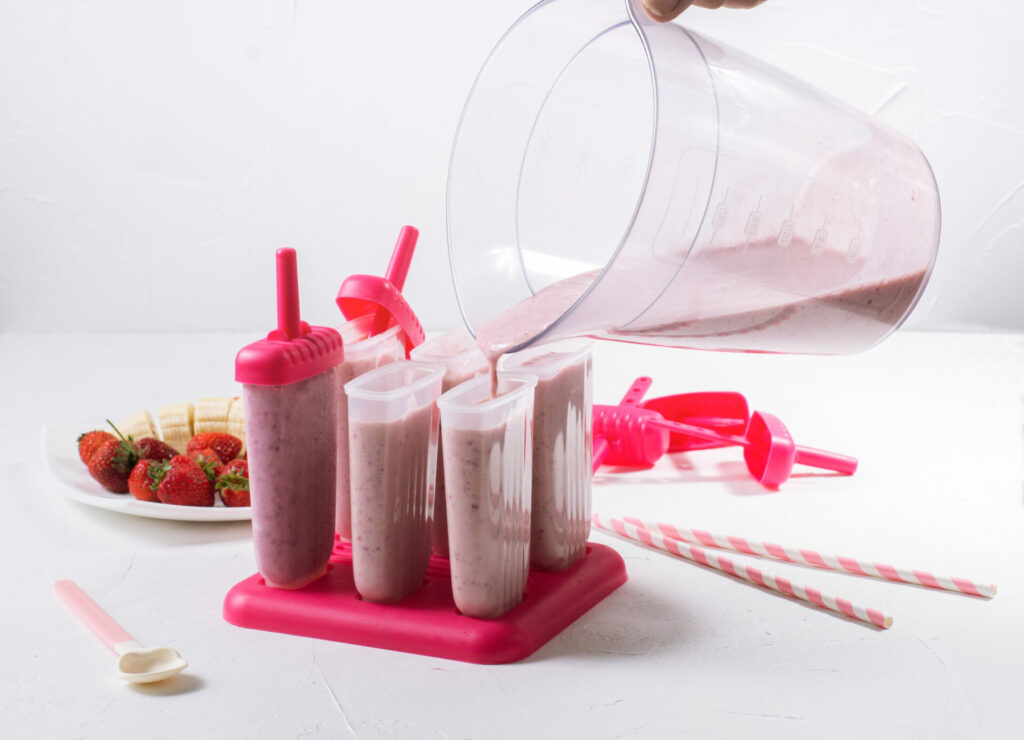 Summer food: cooking home-made fruit ice. Filling the prepared mass in ice cream molds. Close-up.