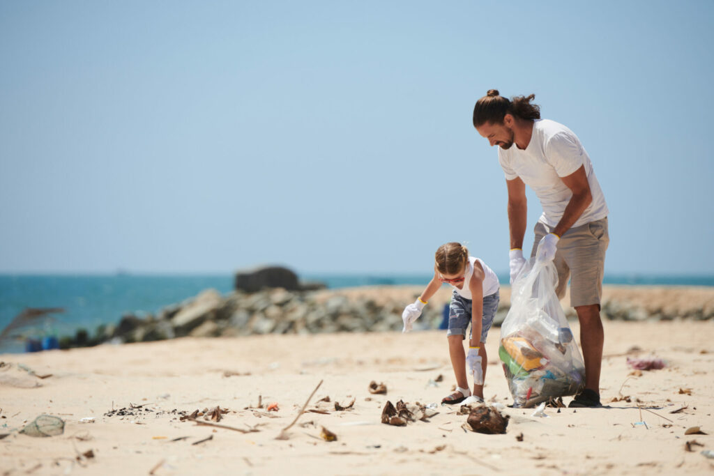 daughter and father doing beach clean up in summer clothes