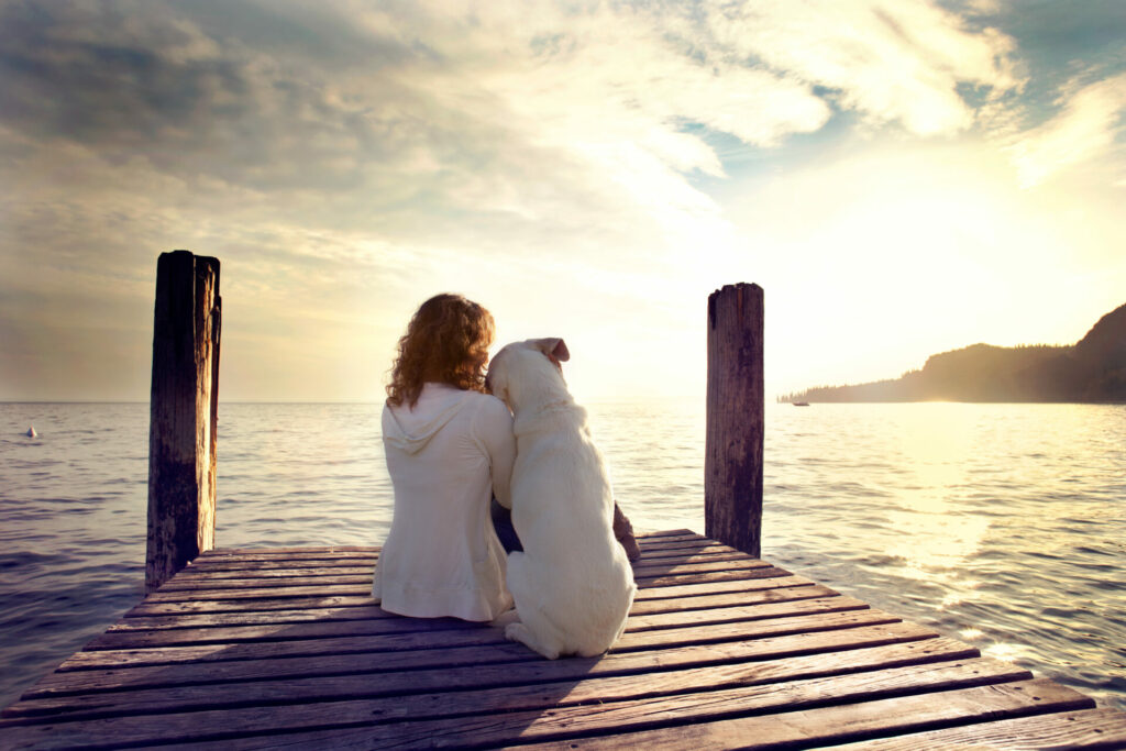 woman cuddling dog on jetty