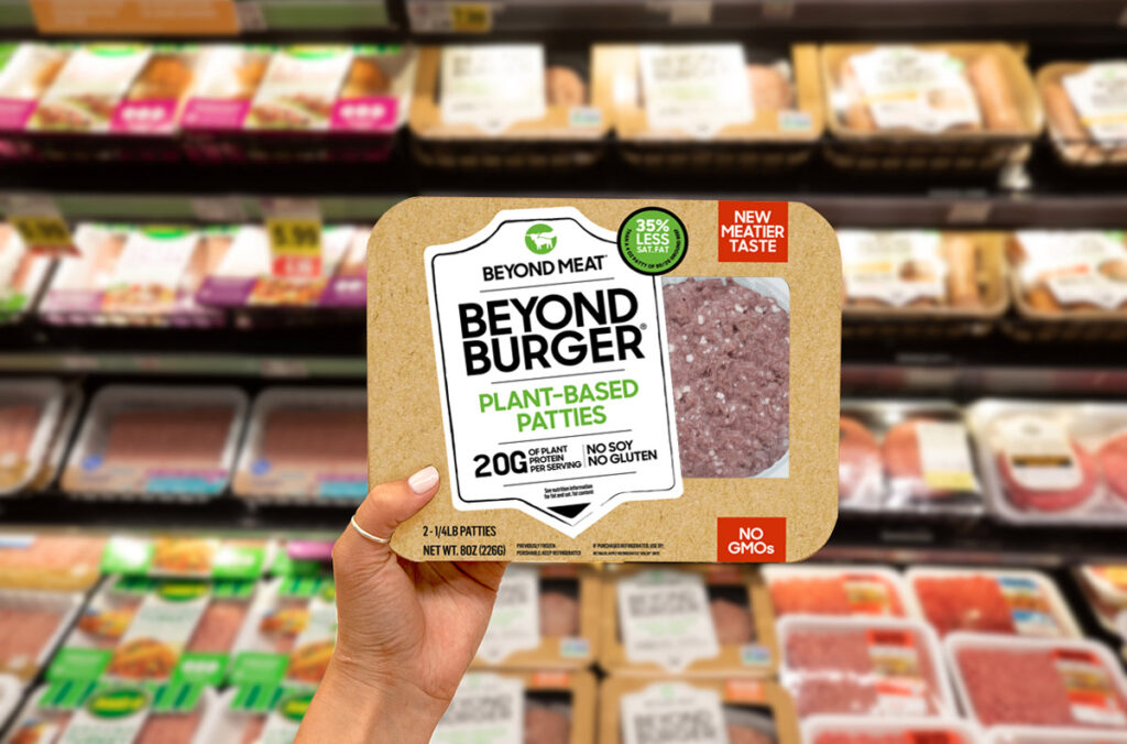 woman holds up Beyond Meat burger pack in supermarket